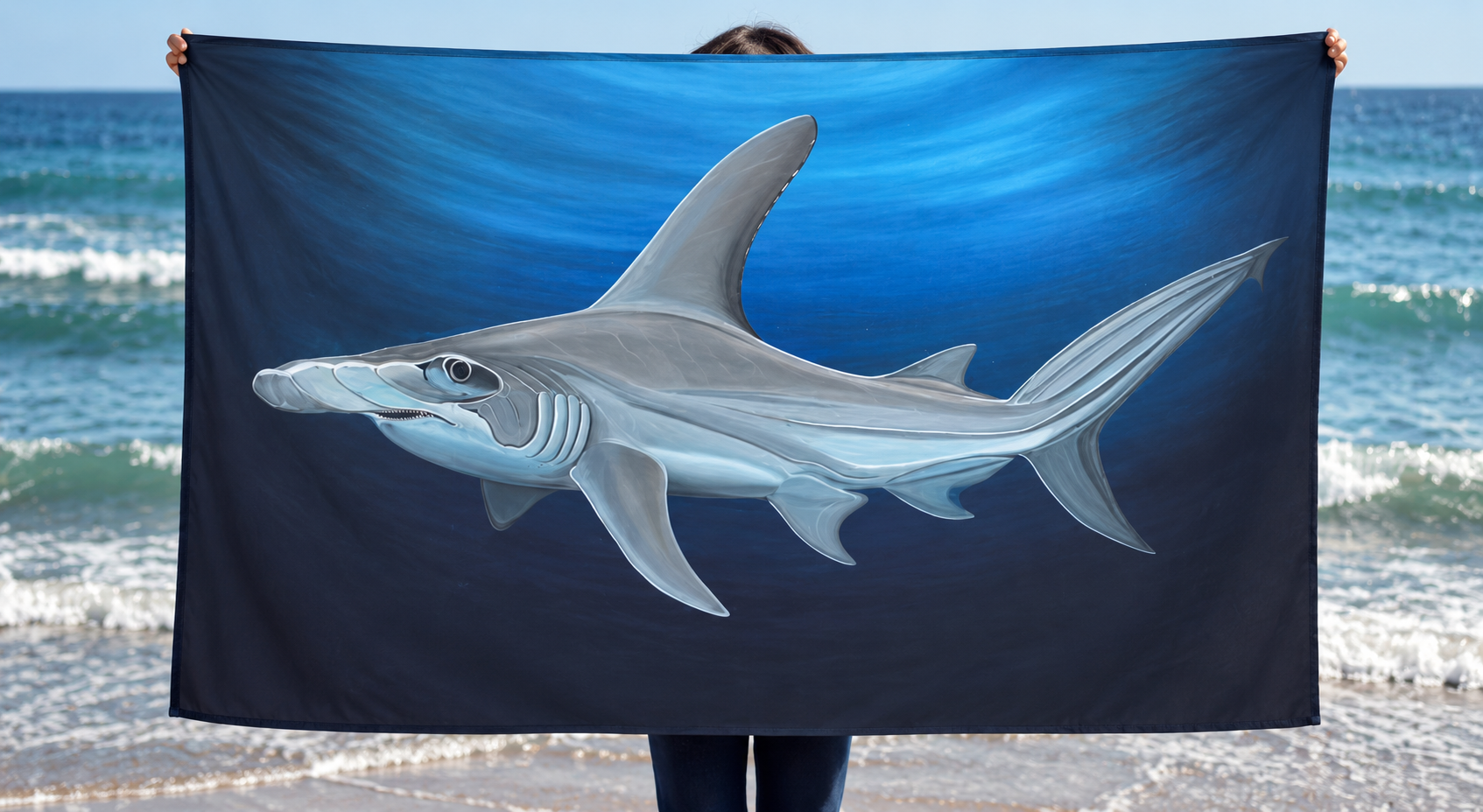 Canga Tubarão grande-martelo estampada com a pintura de Sandy Pintora, segurada na praia