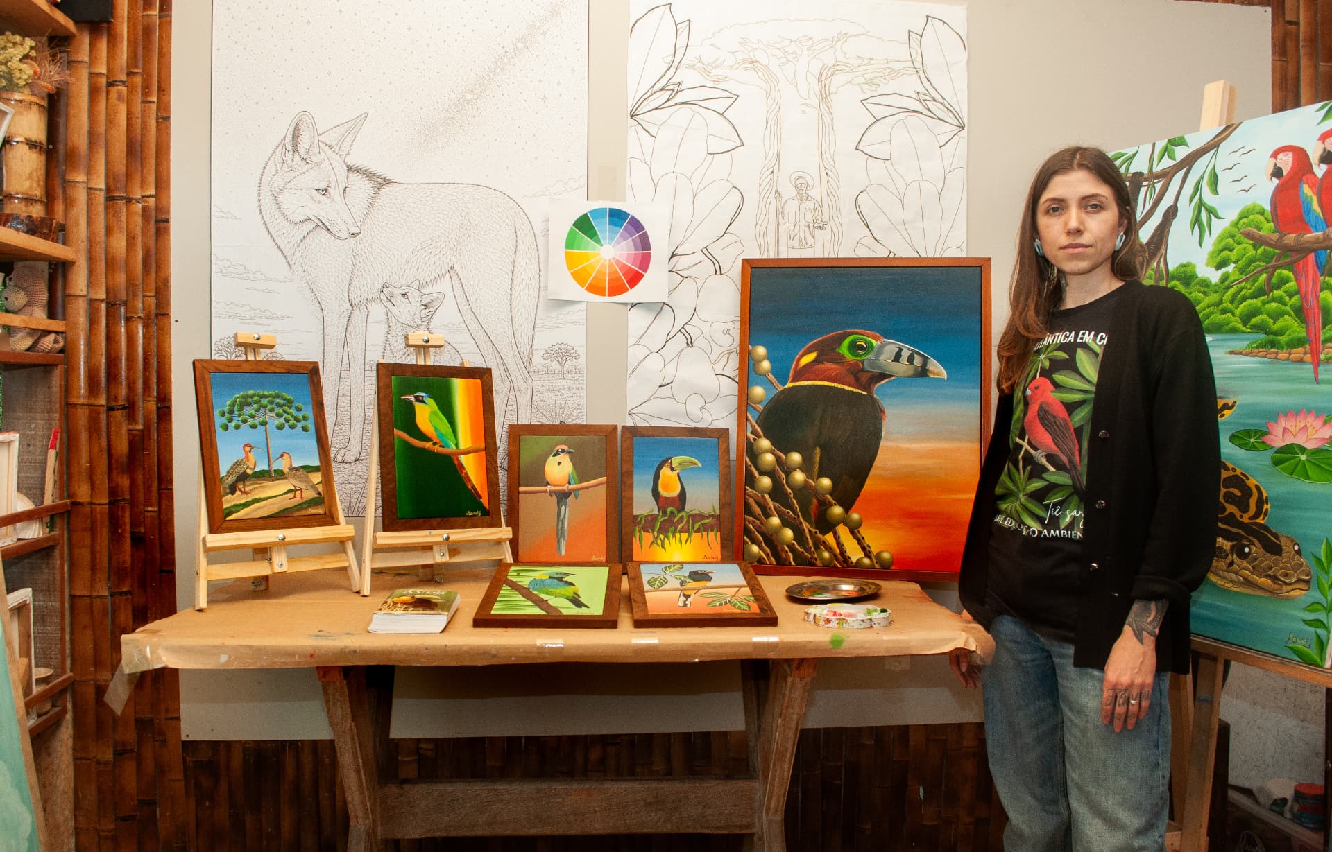 Sandy em seu ateliê diante de estudos e pinturas